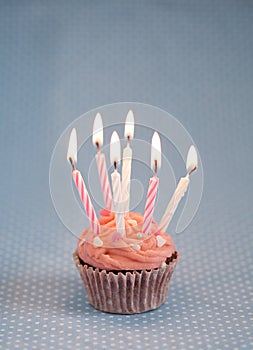 Delicious pink birthday cupcake with candles