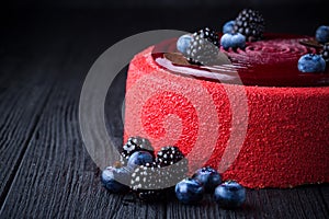 Delicious pink cake with berries on wooden table