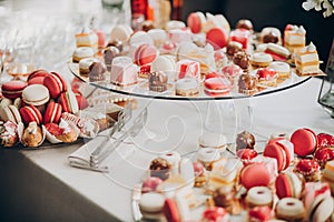 Delicious pink candy bar at wedding reception or christmas celebration. Pink and white macarons,cupcakes, desserts on stand, photo