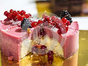 Delicious pink cheesecake with fresh berries on top, on a golden plate