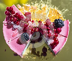 Delicious pink cheesecake with fresh berries on top, on a golden plate