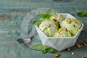 Delicious pistachio ice cream on blue wooden table photo