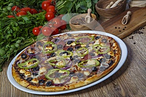 Delicious pizza, glass of beer vegetables and spices on wooden table