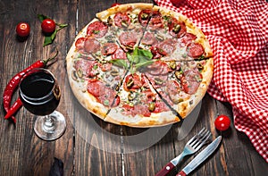 Delicious pizza, glass of wine vegetables and spices on wooden table