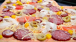 Delicious pizza in a heart shape, ready for baking. Pizza with mushrooms, salami, pepperoni, olives