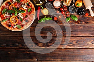 Delicious pizza and ingredients on wooden background photo