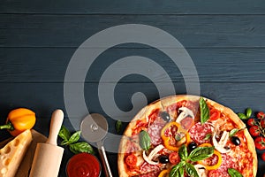 Delicious pizza and ingredients on wooden background photo