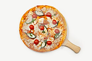 Delicious pizza margarita served on a wooden plate ingredients sauce, basil, mozzarella and cherry tomatoes isolated on