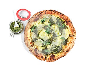 Delicious pizza with pesto, cheese and arugula near jar of sauce on white background, top view