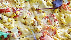 Delicious pizza with tomatoes, meat, corn, bacon and a thick layer of cheese Close-up