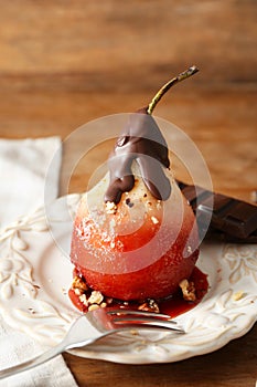 Delicious poached pear in red wine with chocolate sauce on plate