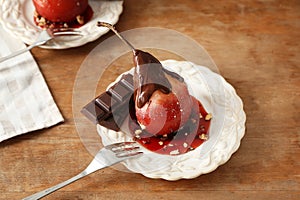 Delicious poached pear in red wine with chocolate sauce on plate