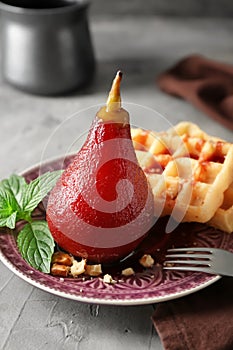 Delicious poached pear in red wine with waffles on plate