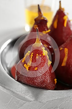 Delicious poached pears in red wine on metal dish, closeup