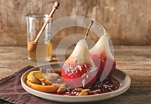 Delicious poached pears in red wine with orange slices and almonds on plate