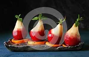 Delicious poached pears in red wine with orange slices on plate