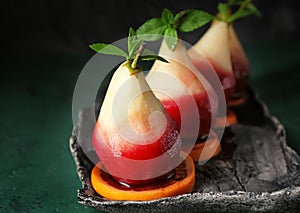 Delicious poached pears in red wine with orange slices on plate