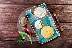 Delicious polenta - Corn porridge hominy with goat cheese, butter and sour cream on wooden background. Healthy food.