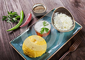 Delicious polenta - Corn porridge hominy with goat cheese, butter and sour cream on wooden background. Healthy food.