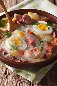 Delicious Polish soup Zurek with sausage and eggs in a bowl. vertical