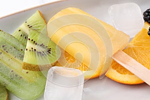 Delicious popsicle, ice cubes and fresh fruits on plate, closeup