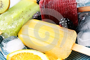 Delicious popsicle, ice cubes and fresh fruits on plate, closeup