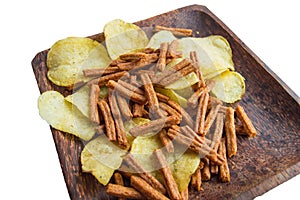 Delicious potato chips and salted rye bread crackers on a dark wooden plate, isolated on a white background by clipping