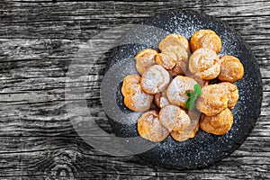 Delicious profiteroles filled with cream on slate plat photo