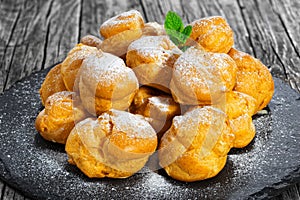 Delicious profiteroles filled with cream on slate plate photo
