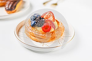 Delicious puff pastry with cream and berries on a white plate