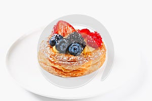 Delicious puff pastry with cream and berries on a white plate