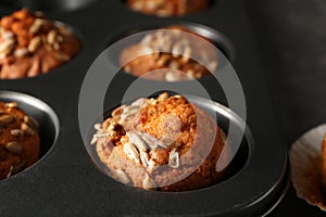 Delicious pumpkin muffins with sunflower seeds in baking form, closeup