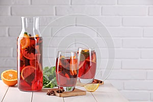 Delicious punch drink, slices of fruits and anise stars on white wooden table. Space for text