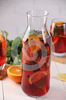 Delicious punch drink and slices of fruits on white wooden table, closeup