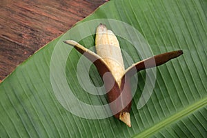 Delicious purple banana and fresh leaf on wooden table, top view
