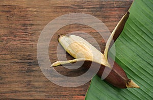 Delicious purple banana and fresh leaf on wooden table, top view. Space for text