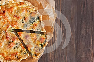 Delicious quiche or tart with vegetables, spinach and cheese on the rustic wooden table