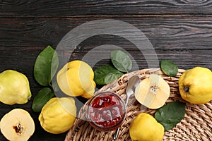 Delicious quince jam and fruits on black wooden table, flat lay. Space for text