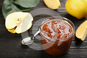 Delicious quince jam and fruits on black wooden table. Space for text