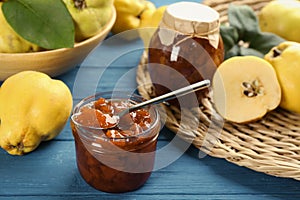 Delicious quince jam and fruits on blue wooden table, closeup