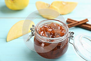 Delicious quince jam  fruits and cinnamon on light blue wooden table