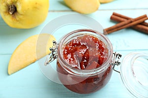 Delicious quince jam, fruits and cinnamon on light blue wooden table