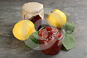 Delicious quince jam and fruits on grey table, closeup