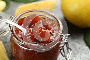 Delicious quince jam and fruits on grey table  closeup