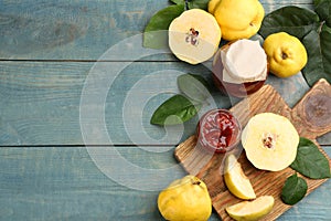 Delicious quince jam and fruits on light blue wooden table, flat lay. Space for text