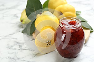 Delicious quince jam and fruits on white marble table, closeup