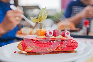 Delicious raspberry pink eclair on a white plate