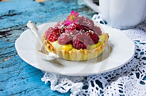 Delicious Raspberry tartlets with vanilla cream on blue wooden background. Top view.