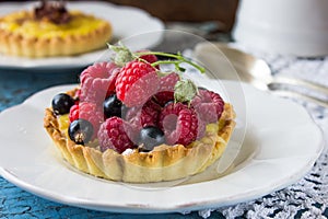Delicious Raspberry tartlets with vanilla cream on blue wooden background. Top view.