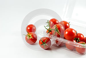 Delicious red tomatoes are housed in a transparent plastic vessel and placed on a white floor, selective focus